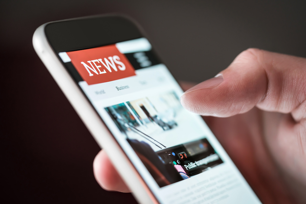 Mobile news application in smartphone. Man reading online news on website with cellphone. Person browsing latest articles on the internet. Light from phone screen. Why You Need a LinkedIn for Your Business News Elle Marketing and Events